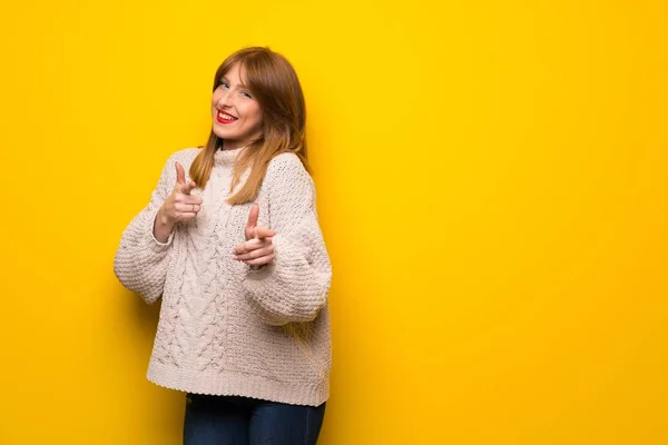 前面と笑顔を指す黄色い壁の上の赤毛の女性 — ストック写真