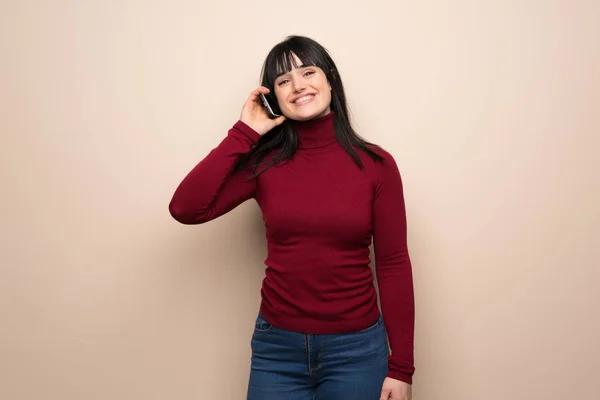 Young woman with red turtleneck keeping a conversation with the mobile phone