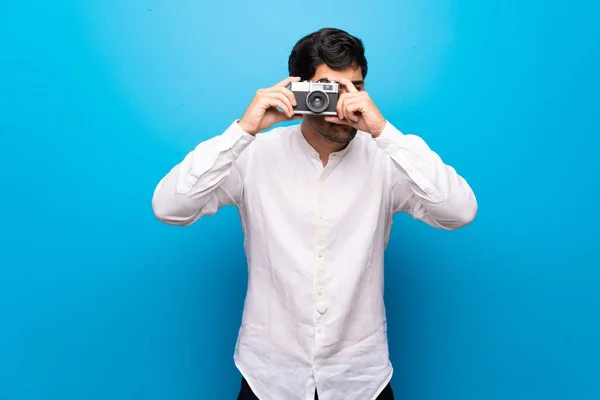 Mladý Muž Nad Izolované Modré Zdi Drží Kameru — Stock fotografie