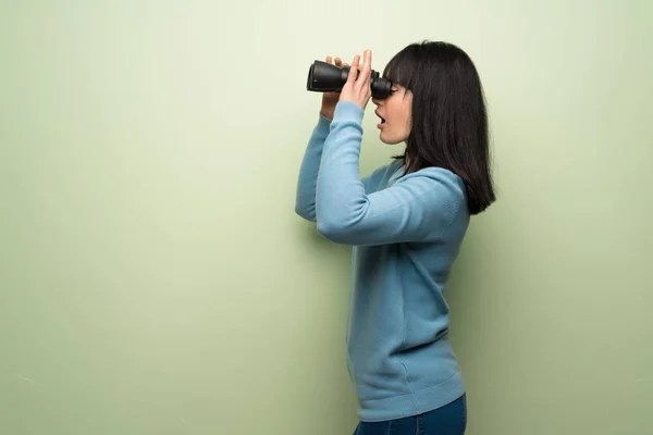 Mujer Joven Sobre Pared Verde Mirando Distancia Con Prismáticos —  Fotos de Stock