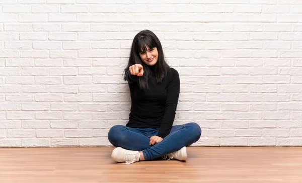 Katta oturan kadın seni kendinden emin bir ifade ile parmak işaret