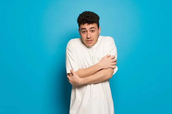 Young man over blue background freezing