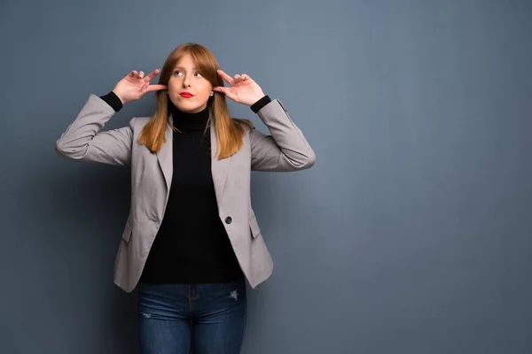 Redhead business woman covering both ears with hands