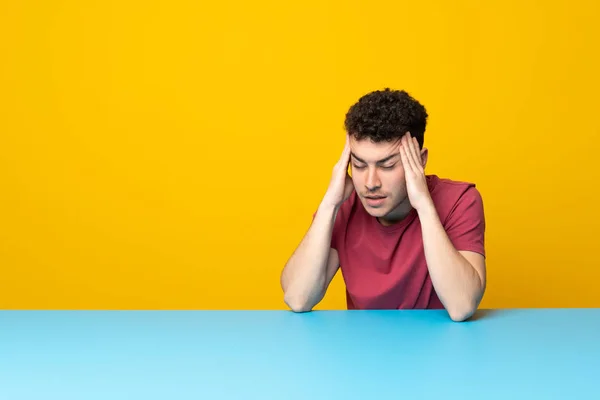 Ung Man Med Färgglad Vägg Och Bord Med Huvudvärk — Stockfoto