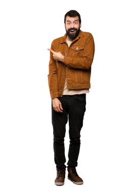 Şaşırttı ve yan izole beyaz arka plan üzerinde işaret sakallı yakışıklı adam