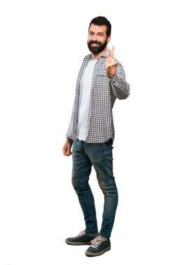 Gülümseyen ve zafer işareti izole beyaz arka plan üzerinde gösterilen sakallı yakışıklı adam