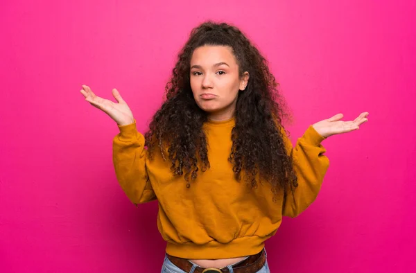 Adolescente Chica Sobre Rosa Pared Teniendo Dudas Mientras Levanta Las —  Fotos de Stock