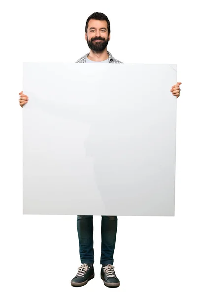 Homem bonito feliz com barba segurando um cartaz vazio — Fotografia de Stock