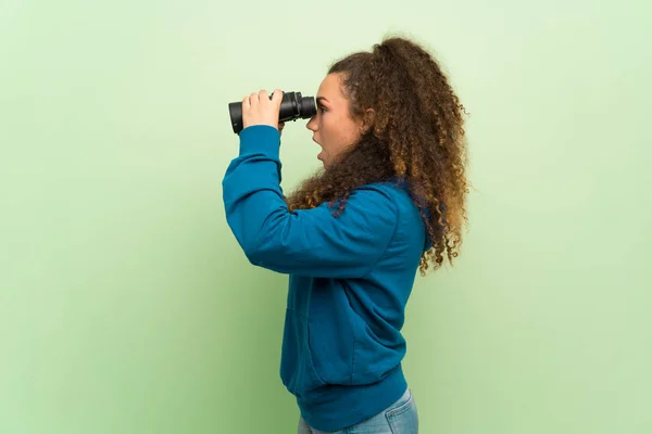 Chica Adolescente Sobre Pared Verde Mirando Distancia Con Prismáticos —  Fotos de Stock