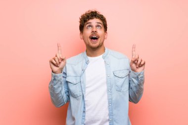 Sarışın adam şaşırttı ve yukarı dönük pembe duvar üzerinde