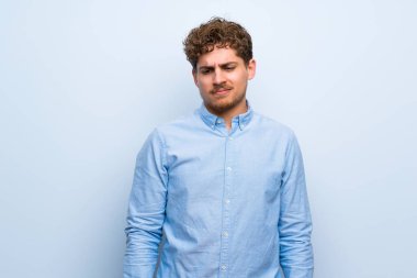 Sarışın adam üzgün ve depresyonda ifade ile mavi duvarın üzerinden