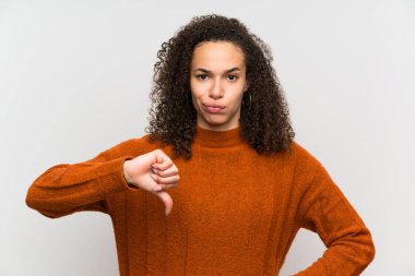 Başparmak işareti aşağı gösteren izole beyaz duvar Dominik kadın