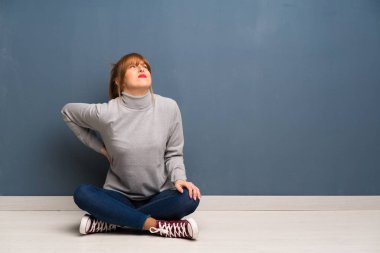 Yerdeki bir çaba yapılmış olması için sırt ağrısı muzdarip siting Kızıl saçlı kadın