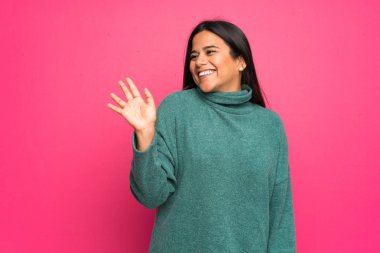 Mutlu ifade ile el ile Saluting yeşil kazak ile genç Kolombiyalı Kız