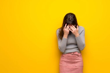 Yorgun ve hasta ifade ile sarı duvarın üzerinden gözlüklü kadın