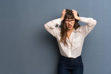 Mavi duvarın üzerinden gözlüklü kadın alır eller başının üstüne çünkü migren vardır