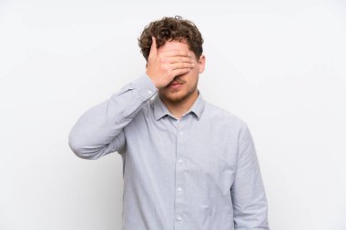 Sarışın adam izole beyaz duvar eller tarafından gözleri kaplama
