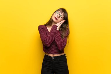 Üzerinde sarı duvar yapım uyku hareketle dorable ifade gözlüklü kadın