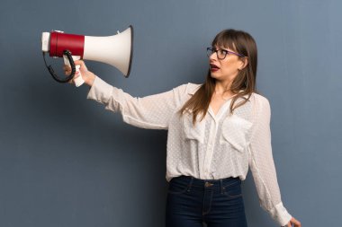 Mavi duvara gözlük ile kadın gürültü bir sürü kılan bir megafon alarak