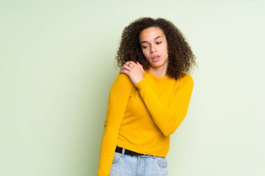 İzole yeşil arka plana sahip yapılmış bir çaba için omuz ağrısı muzdarip Dominik kadın