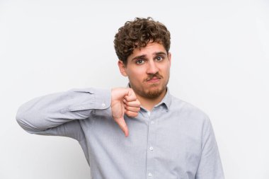 Sarışın adam başparmak işareti aşağı gösteren izole beyaz duvar üzerinde