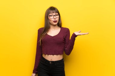 Kadın gözlük boşaltmak hayali avuç içinde tutan sarı duvarın üzerinden bir reklam eklemek için