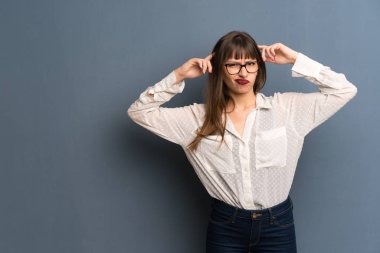 Şüpheleri ve düşünme mavi duvarın üzerinden gözlüklü kadın