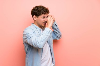 Pembe duvar bir kamera tutarak sarışın adam