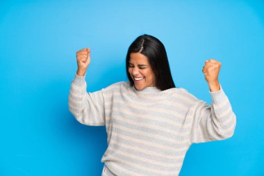 Young Colombian girl with sweater celebrating a victory clipart