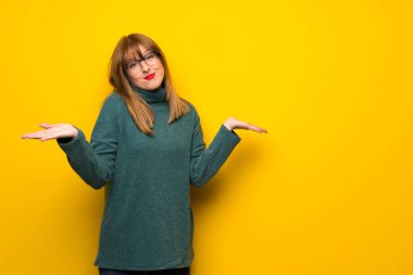 Omuz kaldırma sırasında önemli jest yaparak sarı duvarın üzerinden gözlüklü kadın