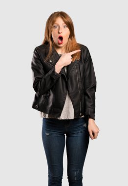 Şaşırttı ve yan izole gri arka plan üzerinde işaret genç Kızıl saçlı kadın