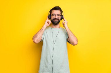 Adam sakallı ve yeşil gömlek kulaklık ile müzik dinlemek
