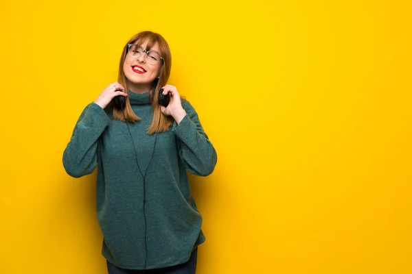 Kulaklıklar Ile Sarı Duvarın Üzerinden Gözlüklü Kadın — Stok fotoğraf