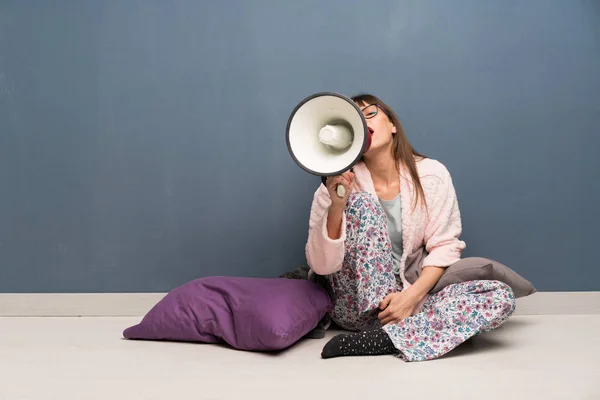 Woman in pajamas on the floor shouting through a megaphone