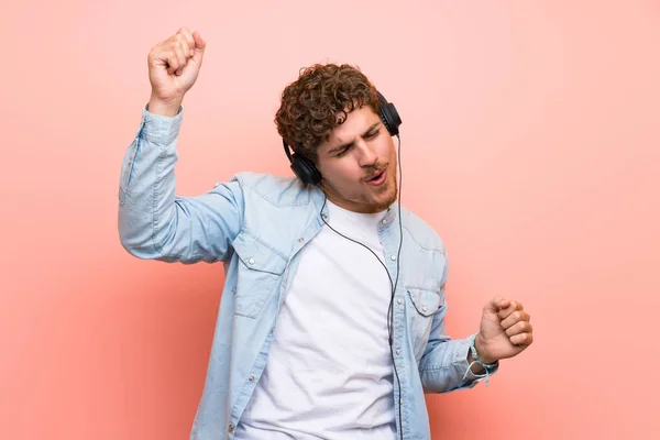 Blonde Man Roze Muur Luisteren Naar Muziek Met Een Koptelefoon — Stockfoto