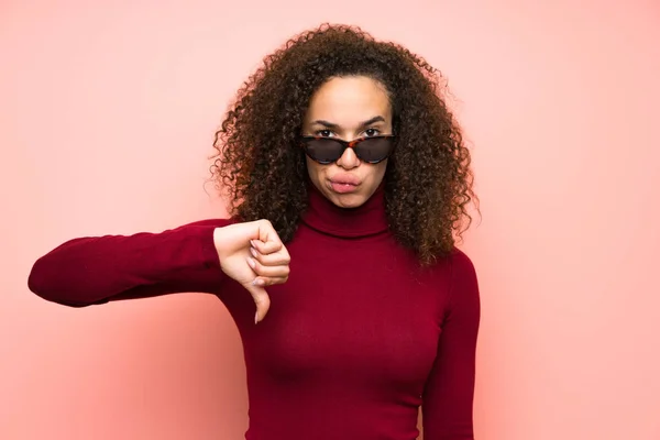 Dominican woman with turtleneck sweater showing thumb down sign