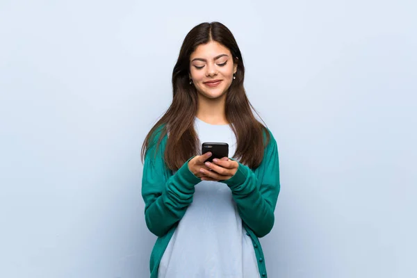 Menina Adolescente Sobre Parede Azul Enviando Uma Mensagem Com Celular — Fotografia de Stock