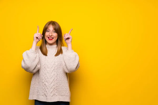 素晴らしいアイデア 人差し指で指している黄色の壁を越えて赤毛の女性 — ストック写真