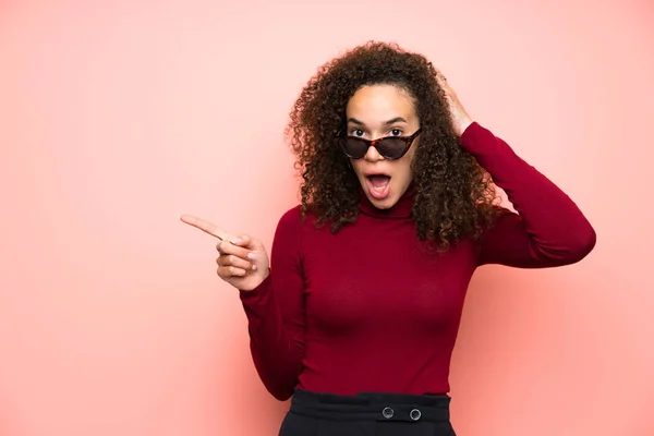 Dominican woman with turtleneck sweater pointing finger to the side and presenting a product