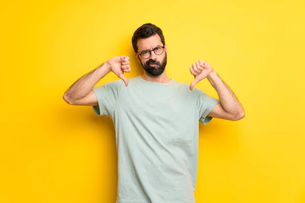 Muž Vousy Zelené Tričko Ukazuje Palec Dolů Oběma Rukama — Stock fotografie