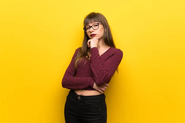 黄色い壁を考える眼鏡をかけた女性 — ストック写真