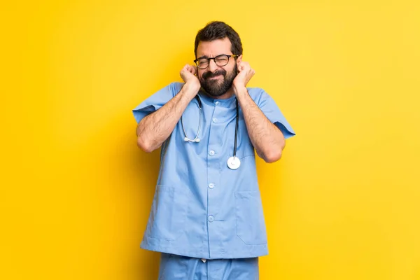 Surgeon doctor man covering ears with hands. Frustrated expression
