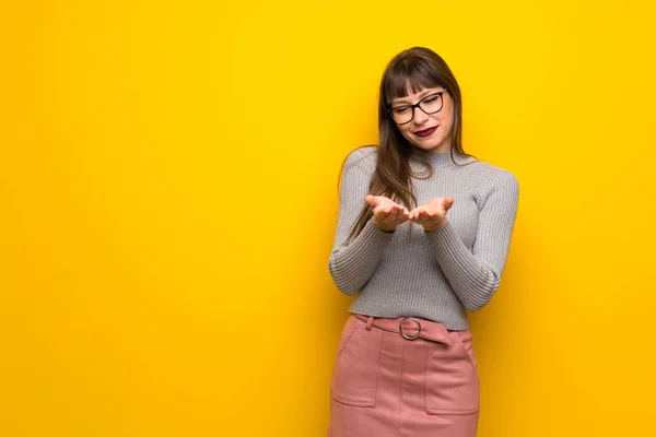Kobieta Okularach Żółte Ściany Trzymając Miejsce Wyobraźni Dłoni Wstawienia Reklamy — Zdjęcie stockowe