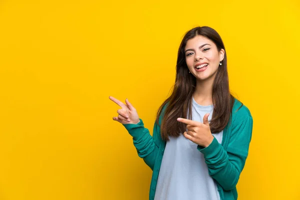 Genç Kız Tarafına Işaret Parmağı Sarı Duvar Üzerinde — Stok fotoğraf