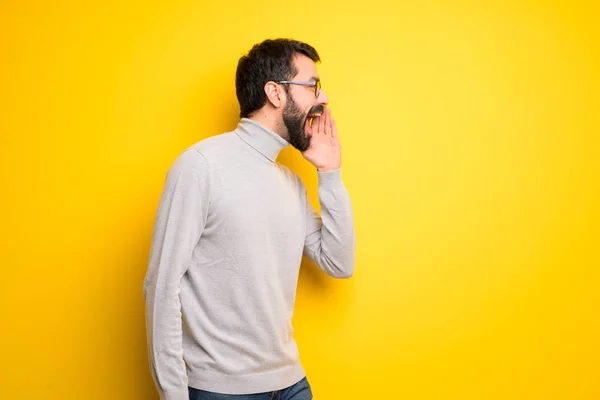 Man with beard and turtleneck shouting with mouth wide open to the lateral