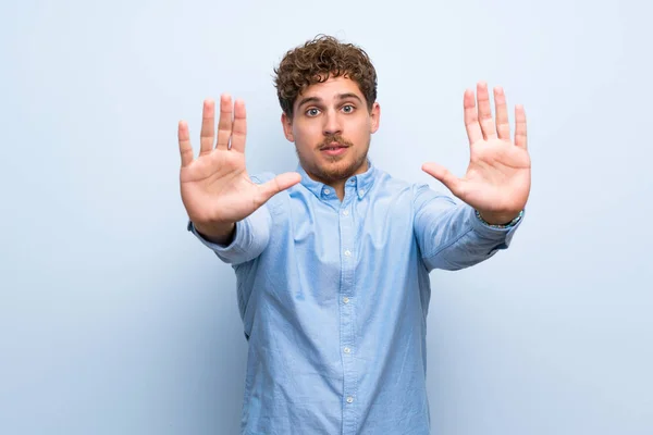 Blond Man Över Blå Vägg Gör Stopp Gest Och Besviken — Stockfoto