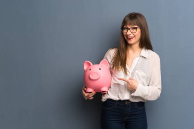 Bir servet tutan mavi duvarın üzerinden gözlüklü kadın