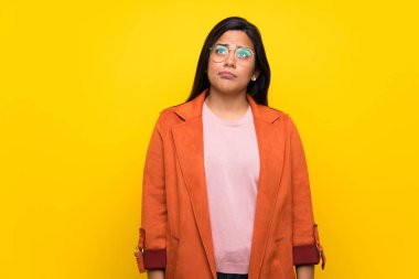 Sarı duvar üzerinde genç Kolombiyalı Kız ciddi yüz ile bakıyor