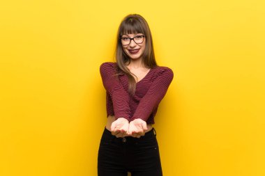 Kadın gözlük boşaltmak hayali avuç içinde tutan sarı duvarın üzerinden bir reklam eklemek için