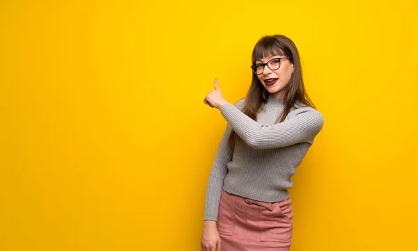 Kobieta Okularach Ścianę Żółty Wskazuje Powrotem Palec — Zdjęcie stockowe